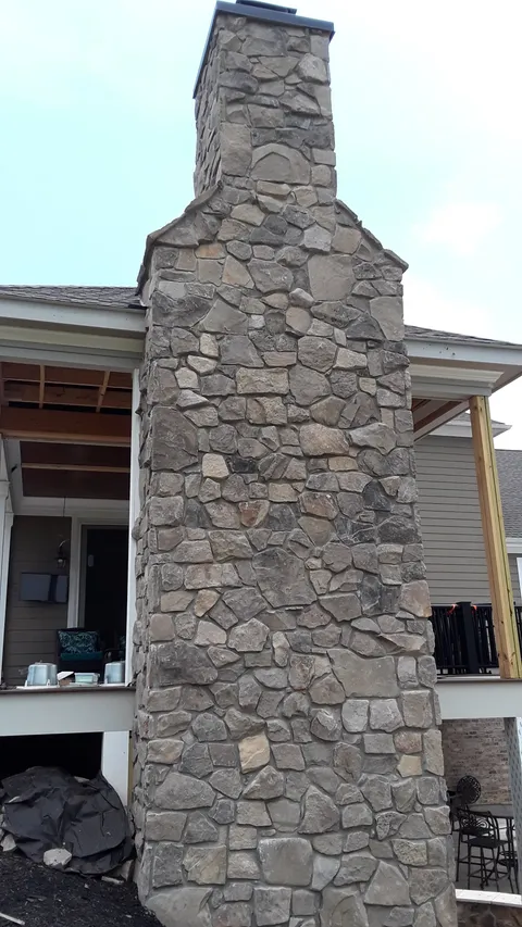 Completed natural stone chimney on a home exterior