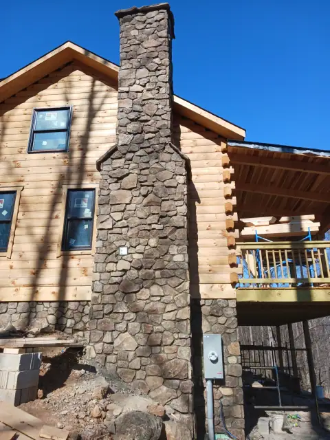 Tall natural stone chimney on a log home