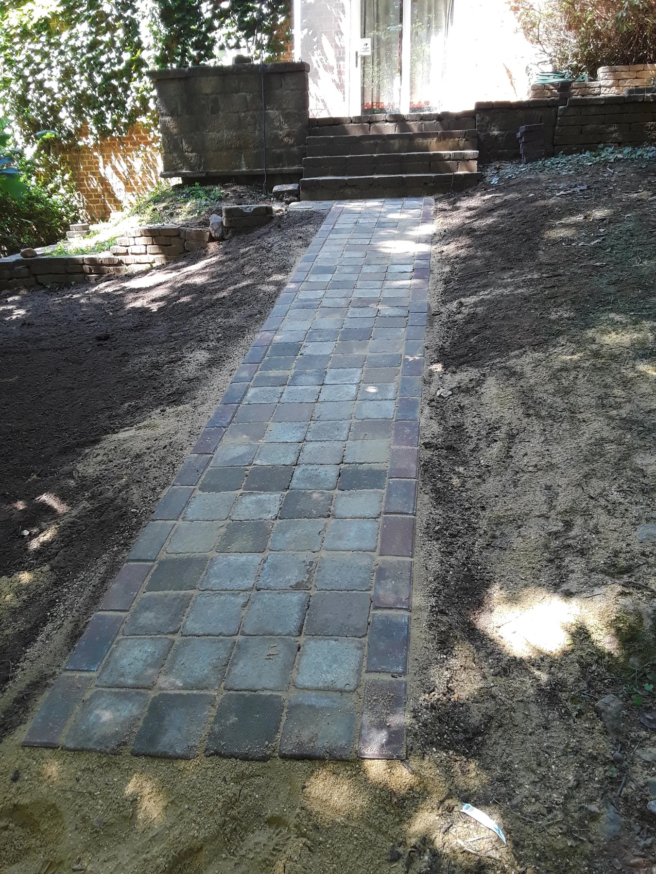 Paver walkway leading to masonry steps and a garden gate