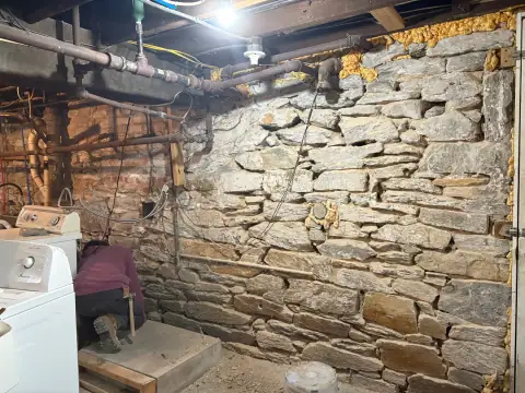 Natural stone basement wall repair near laundry equipment