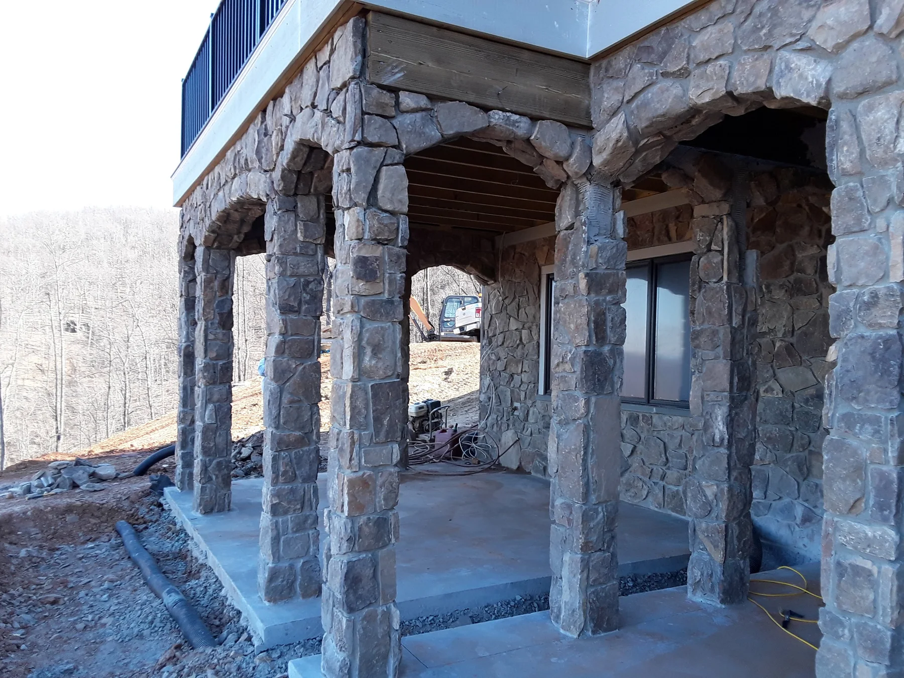 Natural stone columns and arches beneath a raised terrace