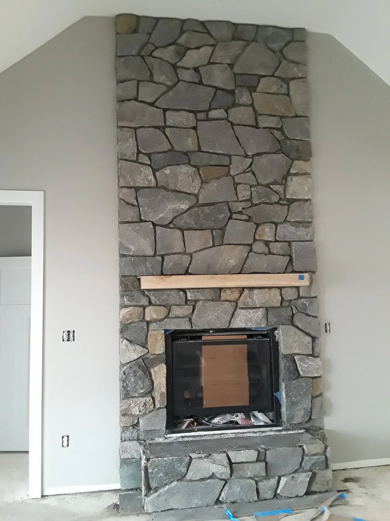 Indoor natural stone fireplace with a wood mantel