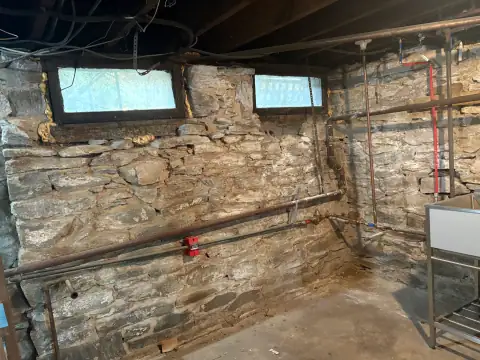 Restored stone basement walls beside a utility sink