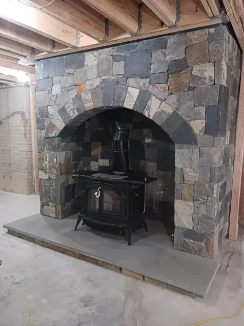 Stone fireplace installation in an unfinished interior