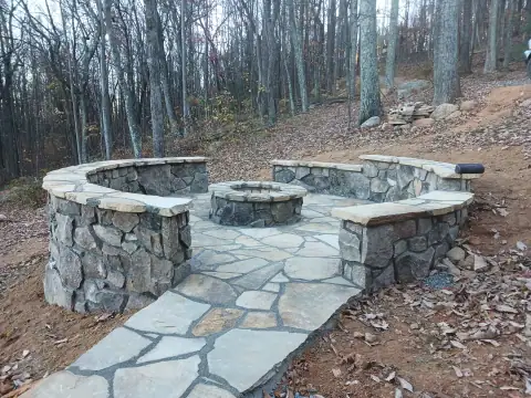 Natural stone patio with a fire pit, seating walls and entrance path by F. Stone Designs