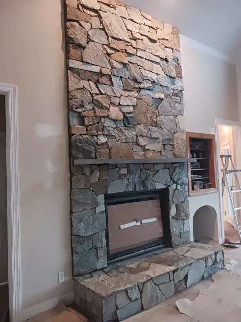 Completed floor-to-ceiling stone fireplace with built-in cabinets