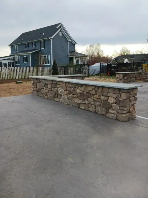 Stone patio and low wall beside a home