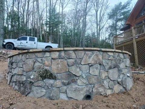 Curved natural stone wall around a raised patio by F. Stone Designs